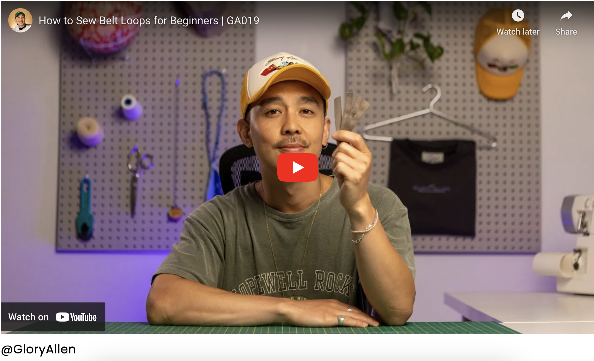 Close-up view of a sewing machine stitching a fabric belt loop onto the waistband of a pair of pants.